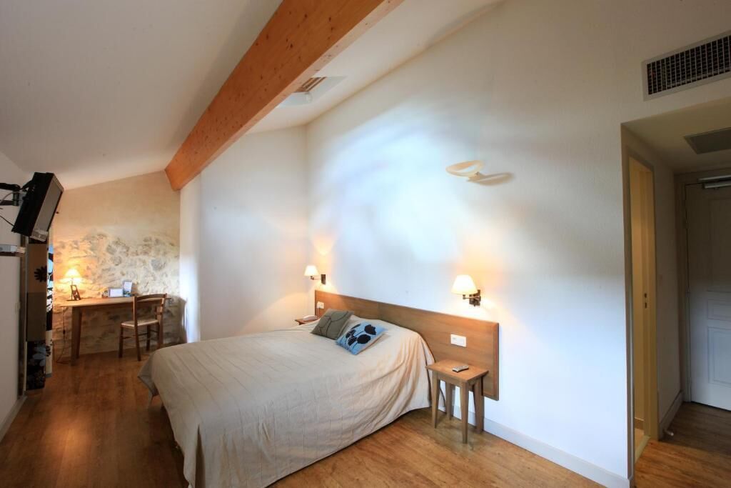 A bedroom with a bed, bedside tables, a desk, and a chair.