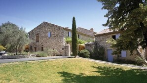 A stone building with a central courtyard, surrounded by trees and a well-maintained lawn. - Domaine les Mejeonnes (Valaurie)