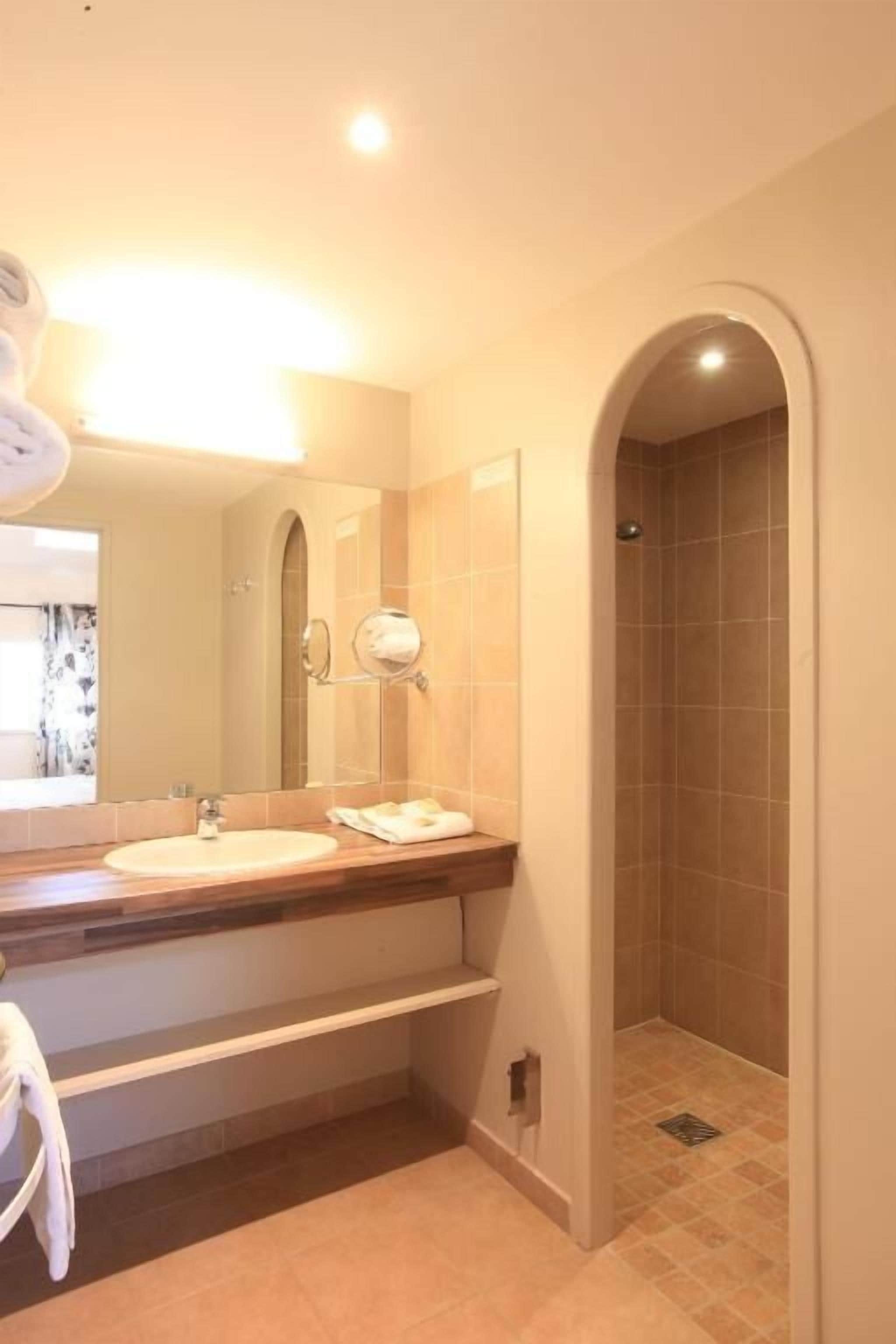 A bathroom with a sink, mirror, and shower.