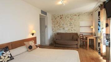 A bedroom with a bed, a sofa, a table, and a chair.