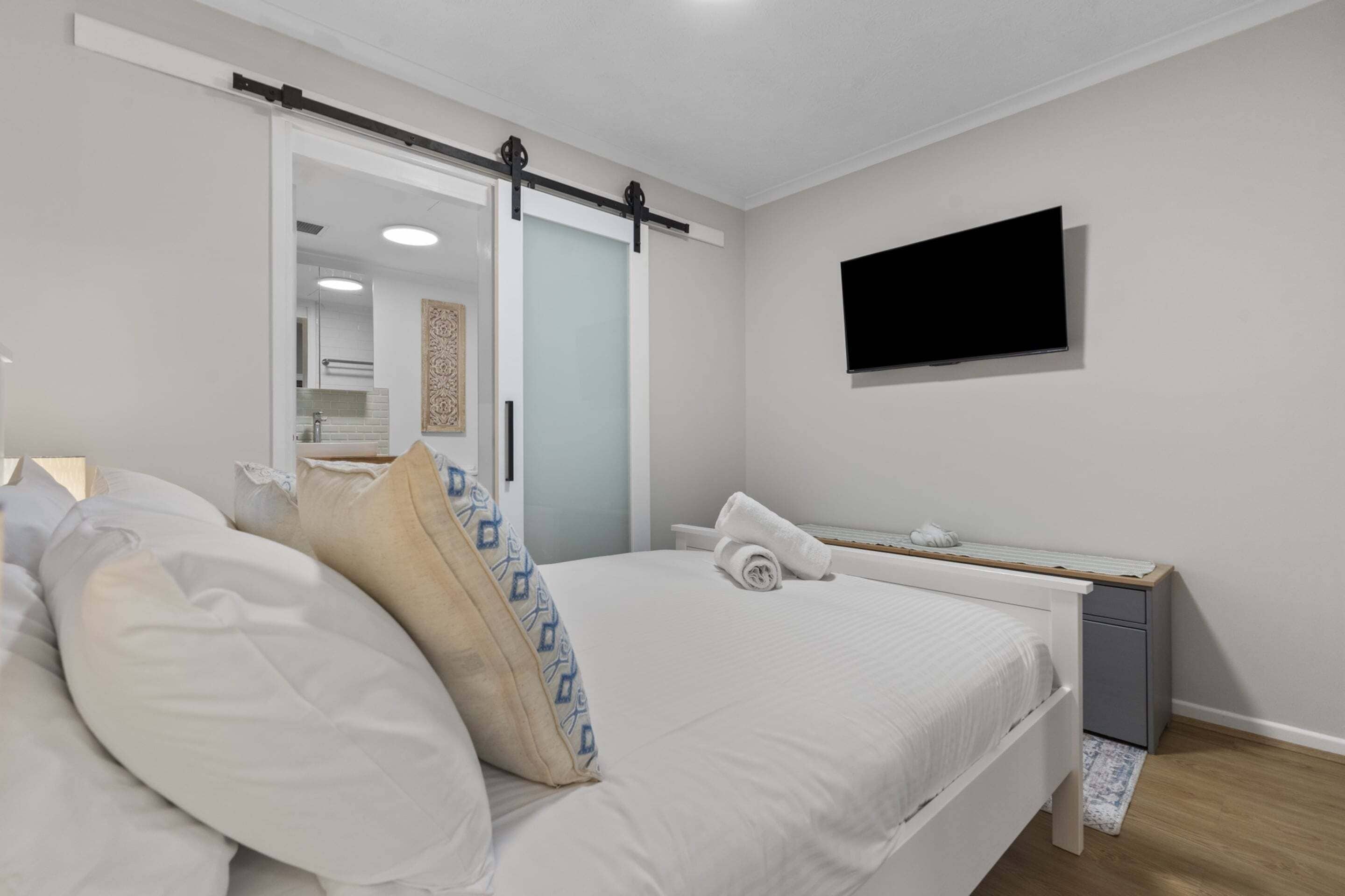 Une chambre à coucher avec un lit, une table de chevet et un téléviseur fixé au mur.