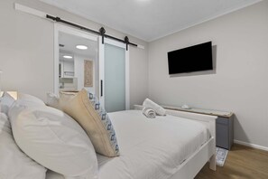 Une chambre à coucher avec un lit, une table de chevet et un téléviseur fixé au mur.