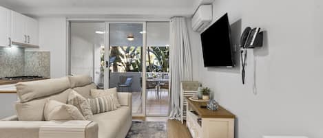 A modern living room with a sofa, a coffee table, and a TV mounted on the wall.
