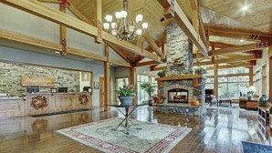 Eine geräumige Lobby mit Kamin aus Stein, Holzbalken und einer Rezeption.