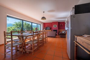 Une cuisine moderne avec un coin repas, de grandes fenêtres et une vue sur la verdure.