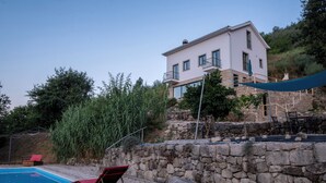 Une maison à deux étages avec un mur en pierre et une piscine.