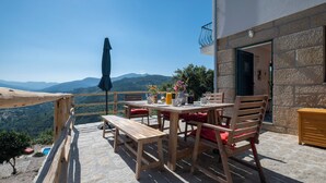 Un espace extérieur aménagé en bois, avec une table et des chaises, un banc et un parasol.