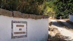 Une enseigne sur un mur blanc orné de carreaux décoratifs, sur laquelle on peut lire : « QUINTA DA MADRUGADA ».