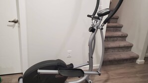 Una bicicleta estática en una habitación con una puerta blanca y una escalera.