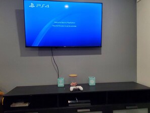 Een PlayStation 4 console op een zwarte entertainmentkast, met een televisie waarop het PS4-logo en een welkomstbericht staan.