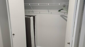 Un closet amplio con barra para colgar ropa y un perchero con prendas dobladas.