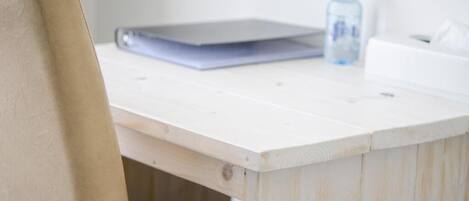 A wooden desk with a laptop and a water bottle.