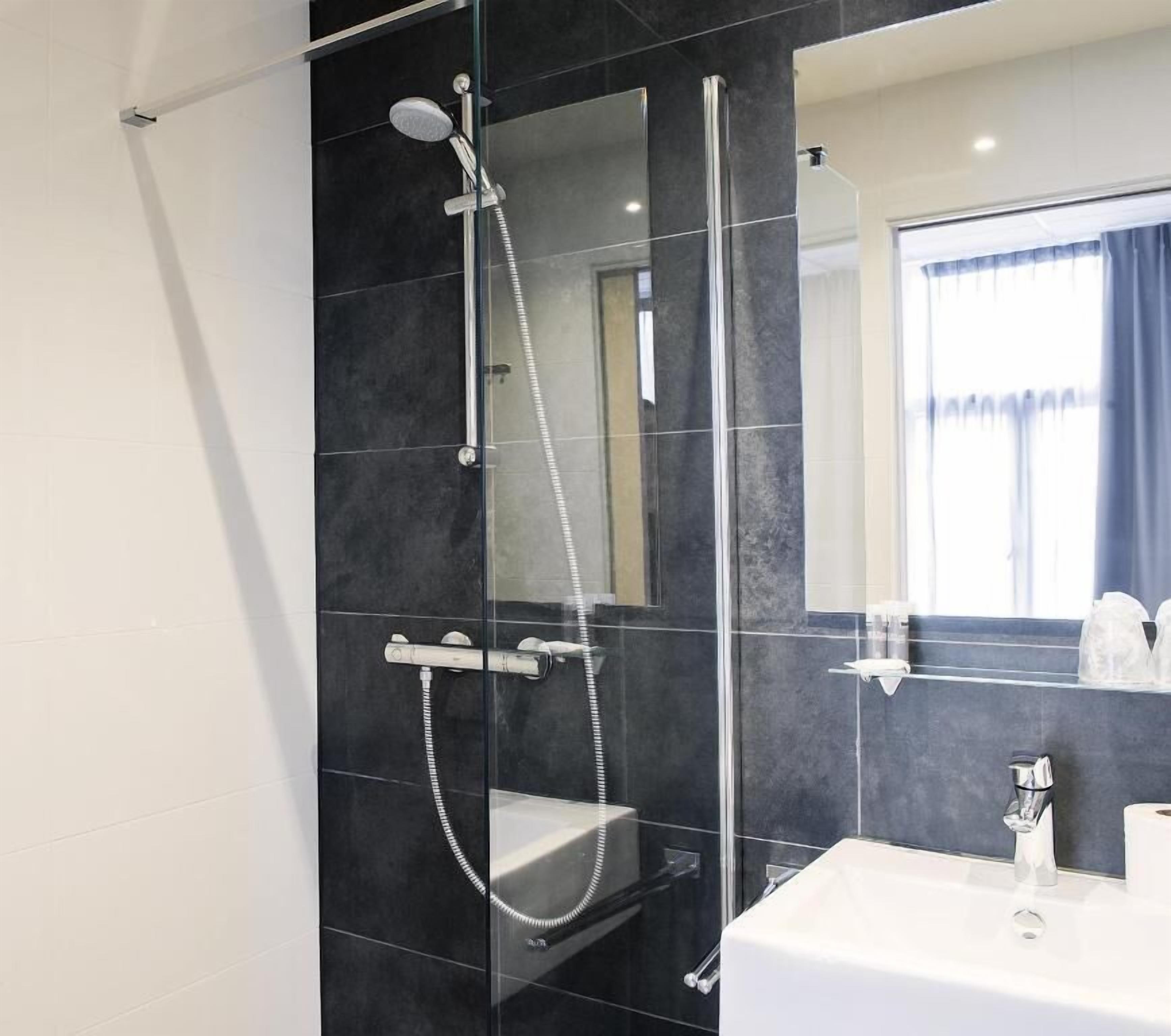 A modern bathroom with a glass-enclosed shower, a white sink, and a mirror above the sink.