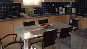 Eine moderne Küche mit Holzausstattung, einem Glastisch und einer Deckenleuchte.