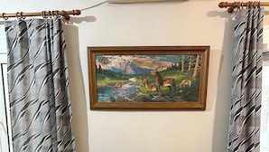 A living room with a sofa, a painting, and curtains. - Cozy Apartment in the Heart of Athens (Zografos)