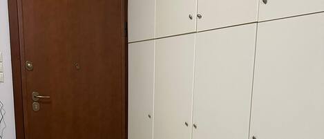 A room with a brown door, a white wardrobe with multiple drawers, and an EXIT sign on the wall.