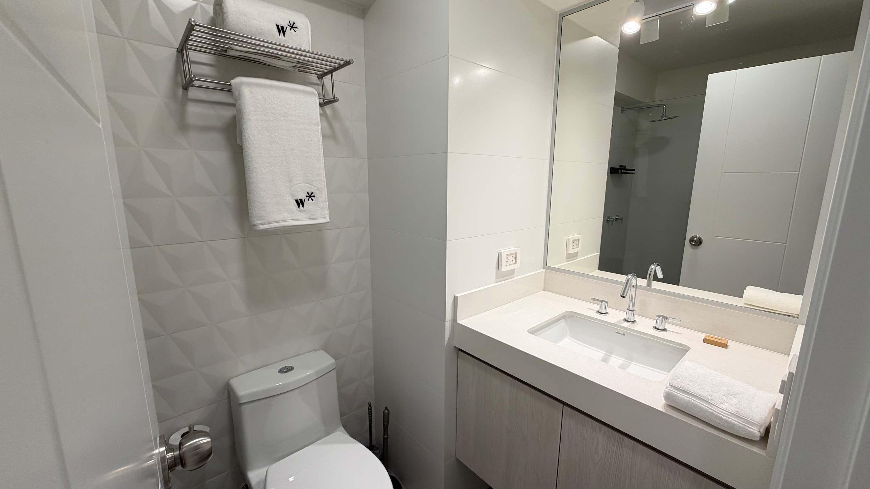 Uma casa de banho moderna com sanita, lavatório e chuveiro.