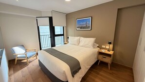 A bedroom with a bed, a chair, a nightstand, a lamp, and a picture on the wall. - w Amazing and Cozy 2BR w Balcony in Miraflores (Lima)