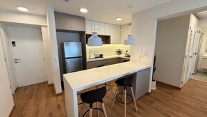 A modern kitchen with a white countertop, two bar stools, a double-door refrigerator, and pendant lighting. - w Amazing and Cozy 2BR w Balcony in Miraflores (Lima)