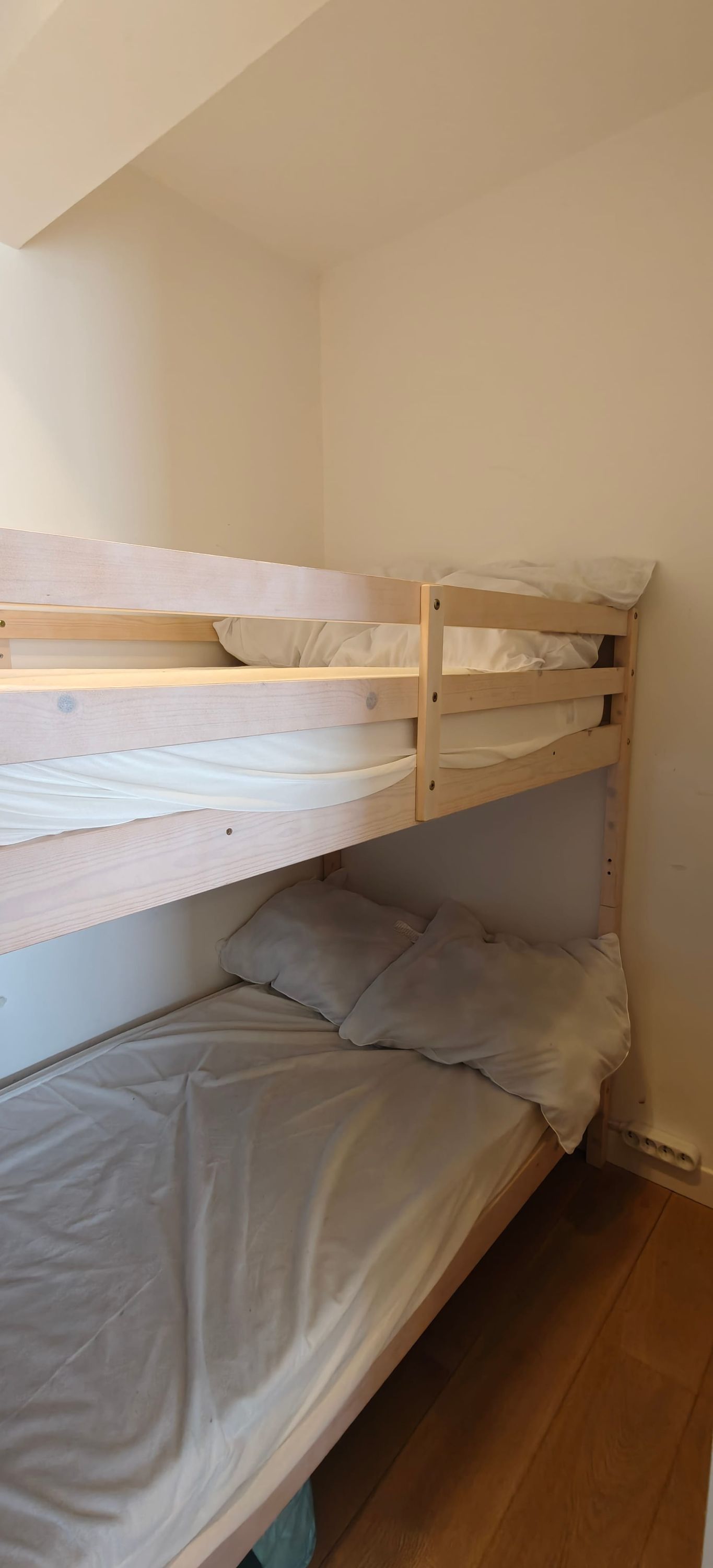 Ein Etagenbett mit zwei Schlafstellen, einem Einzelbett unten und Holzboden.