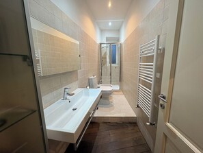 Une petite salle de bain avec un lavabo blanc, des toilettes et une cabine de douche en verre.