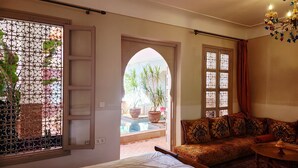 Un dormitorio con cama, sofá y vista a un área de piscina exterior.