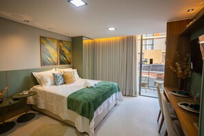 A modern bedroom with a large bed, a dining table with chairs, and a balcony with a view. - Setai Aquamaris #120 - Seafront by Carpediem (João Pessoa)