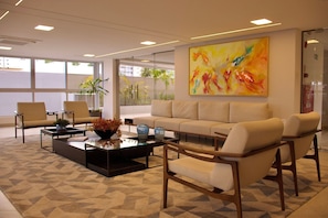 A modern waiting area with a sofa, chairs, and a coffee table. - Puerto Ventura #401a - Apto 2 Quartos by Carpediem (João Pessoa)