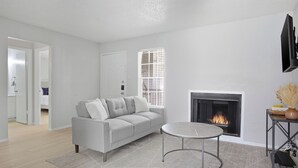 Un salon moderne avec un canapé gris, une table basse ronde, une cheminée et un téléviseur fixé au mur.