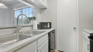Une cuisine moderne équipée d’un évier à deux bacs, d’un four à micro-ondes et d’un lave-vaisselle.