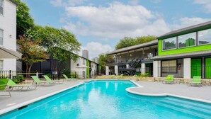 Une piscine avec des chaises longues et un bâtiment à la façade verdoyante.