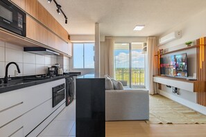 Eine moderne Küche mit schwarzem Arbeitsplatz, weißen Schränken und einem eingebauten Ofen. Ein großes Fenster bietet einen Ausblick ins Freie.