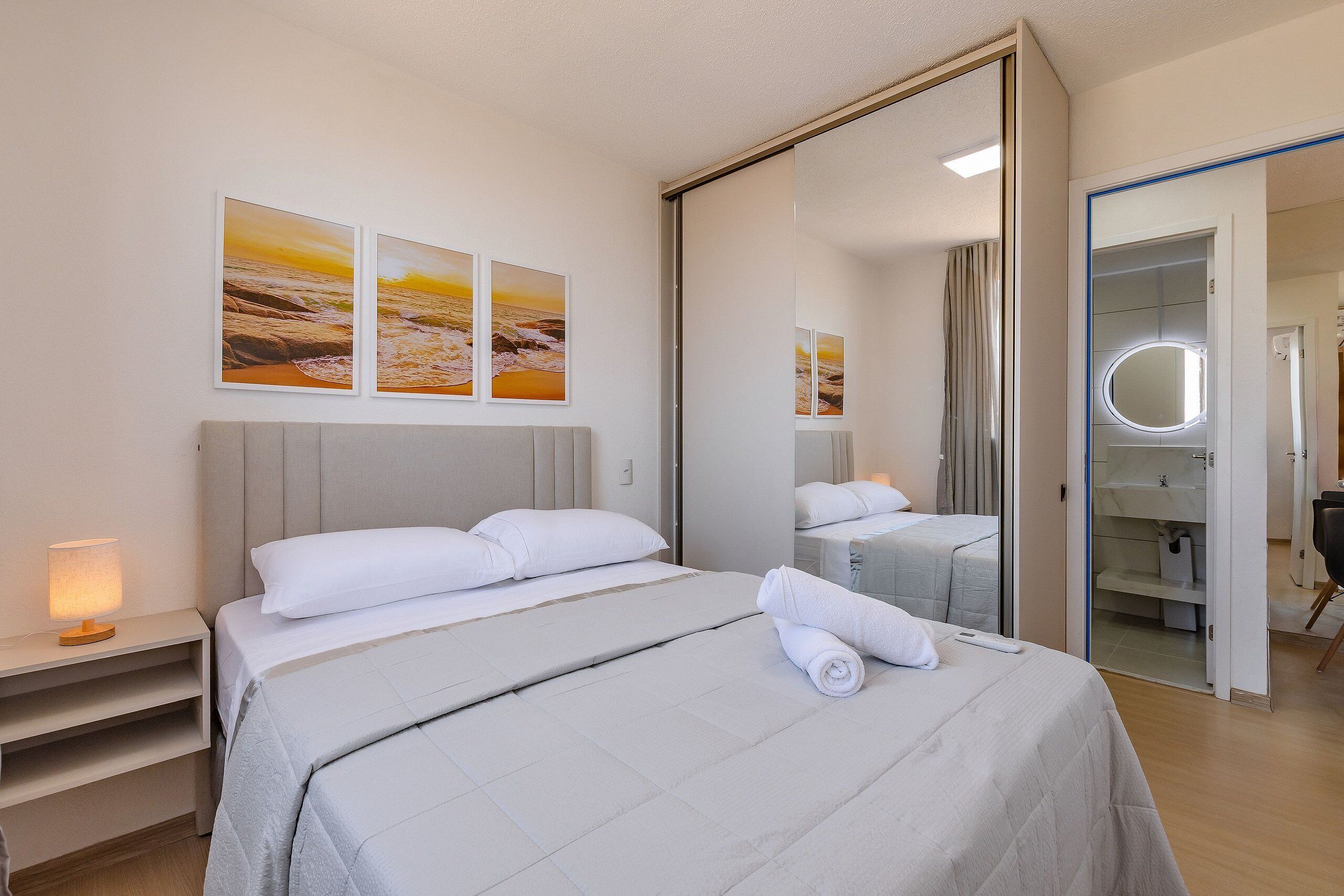 Ein Hotelzimmer mit Bett, Nachttisch, Spiegel und Bildern an der Wand.