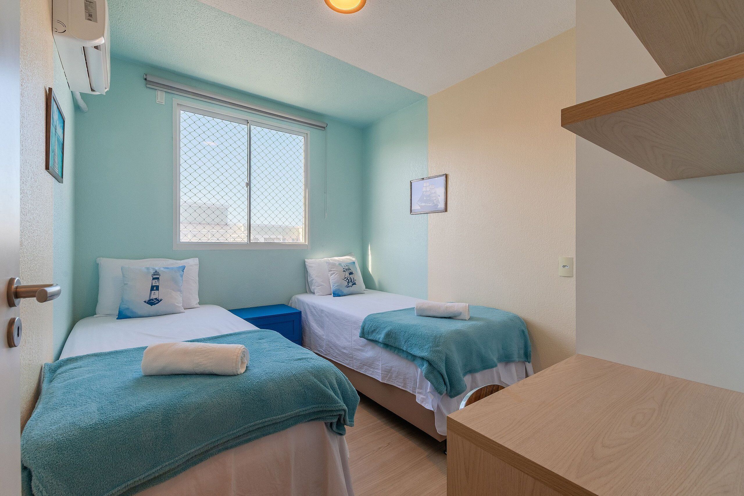 Una habitación con dos camas, una ventana y un escritorio de madera.