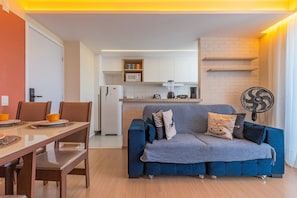 A compact living space with a dining area, kitchenette, and a sofa with cushions. - Mirante #1401 - Complete Apartment by Carpediem (Fortaleza)