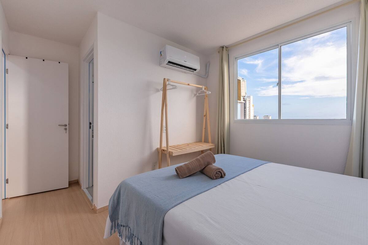 Ein Schlafzimmer mit einem Bett, einem Holztrockner und einem Fenster mit Blick auf die Stadt.