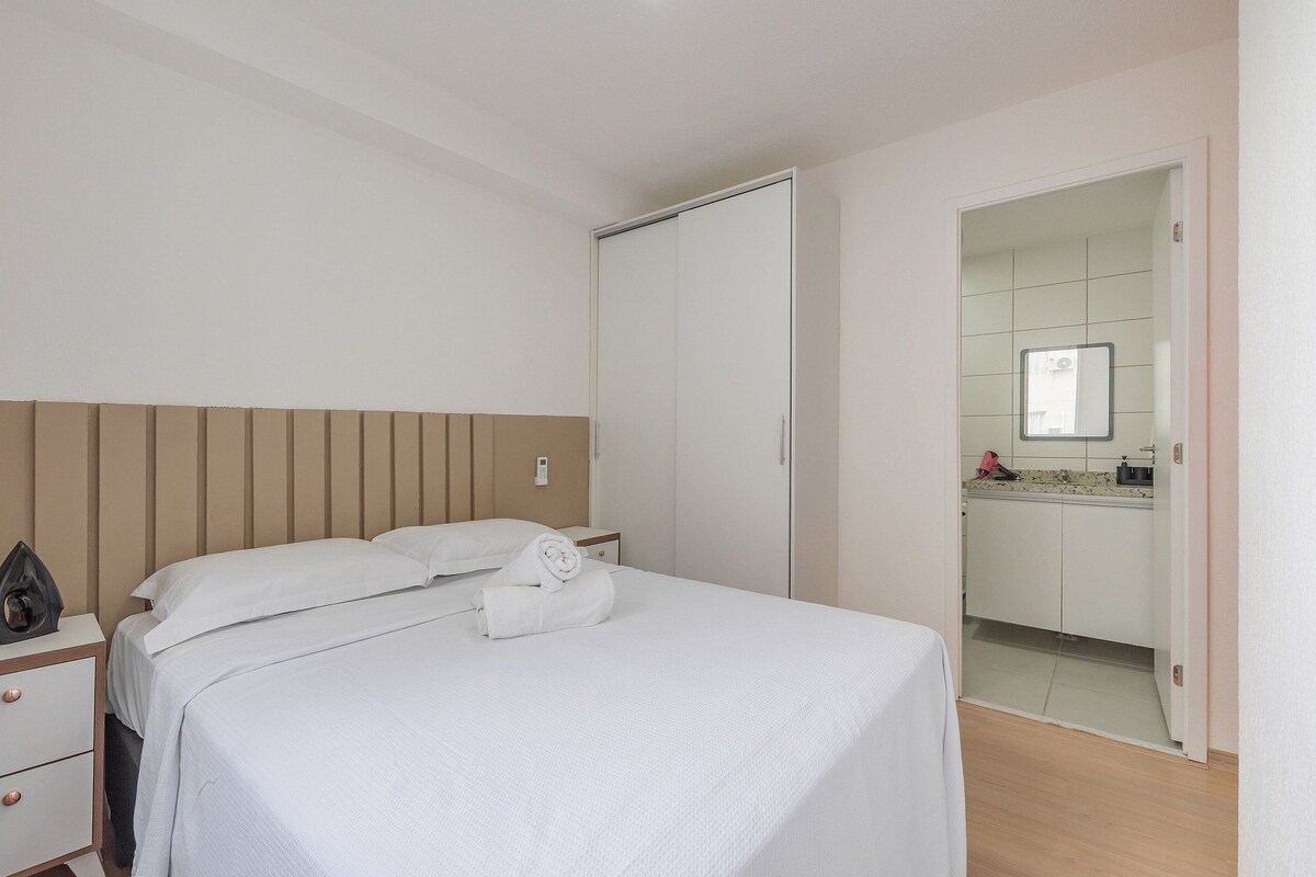 Ein Schlafzimmer mit Bett, Nachttisch, Kleiderschrank und Blick ins Badezimmer.