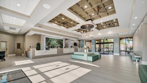 Un'ampia hall con reception, angolo salotto e grandi finestre che lasciano entrare la luce naturale.