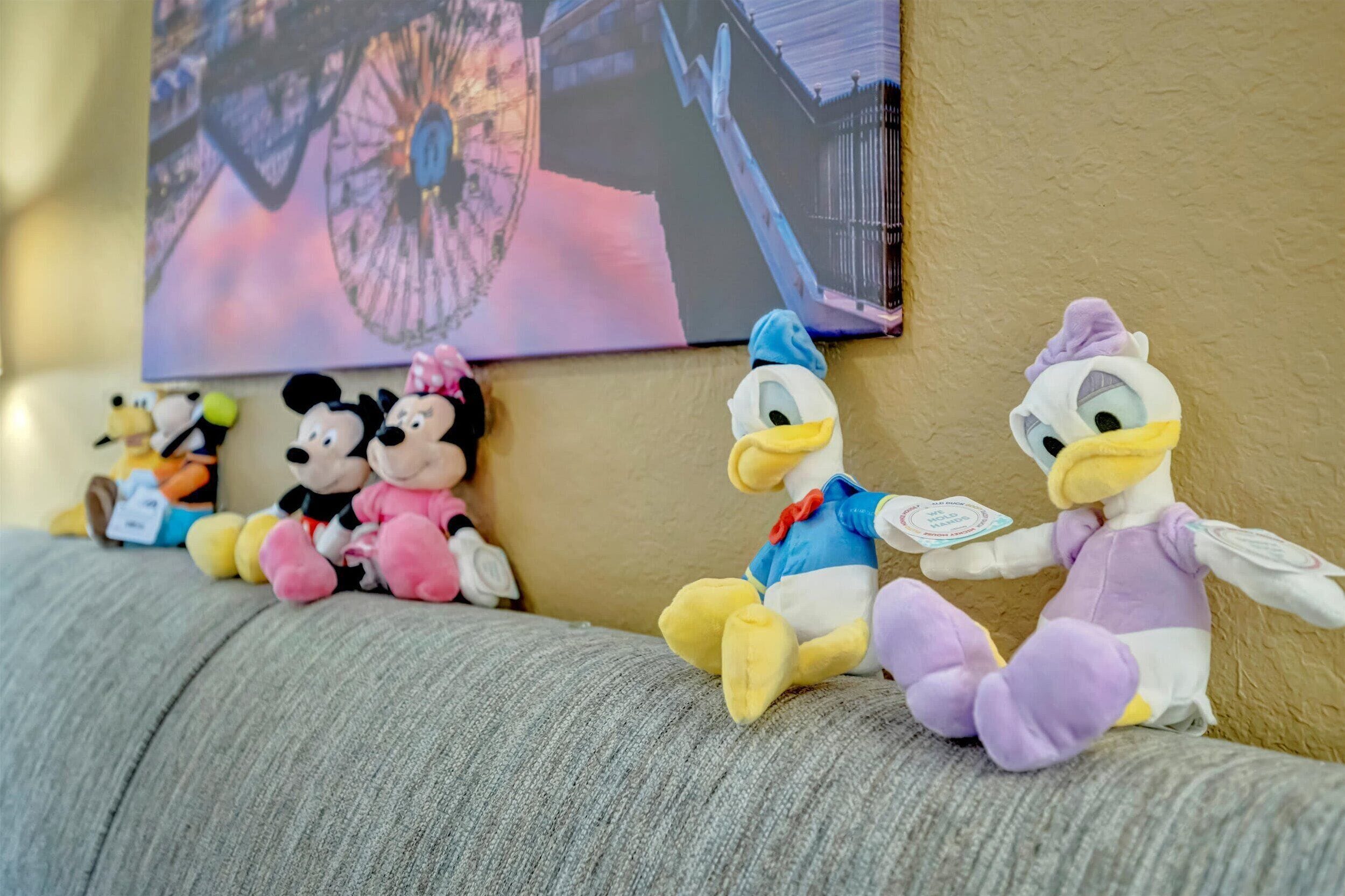 Plush toys arranged on a sofa against a wall with a painting.