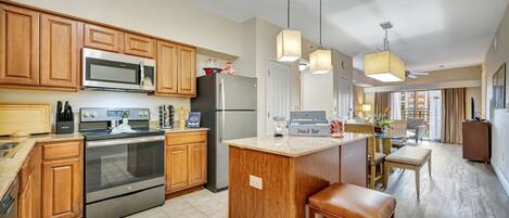A modern kitchen with wooden cabinets, stainless steel appliances, and a central island with stools.