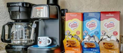 A Keurig coffee maker, a mug, and three boxes of Nestlé Coffee Mate creamer.