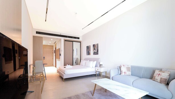 A modern hotel room with a bed, a sofa, a coffee table, and a TV. - Stayshort - Amazing Studio in JVC That Sleeps 2 With Balcony (Dubai)