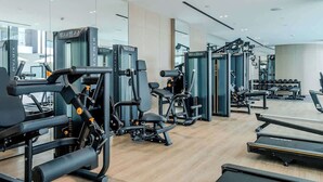 A modern gym with various exercise machines, treadmills, and free weights. - Stayshort - Amazing Studio in JVC That Sleeps 2 With Balcony (Dubai)