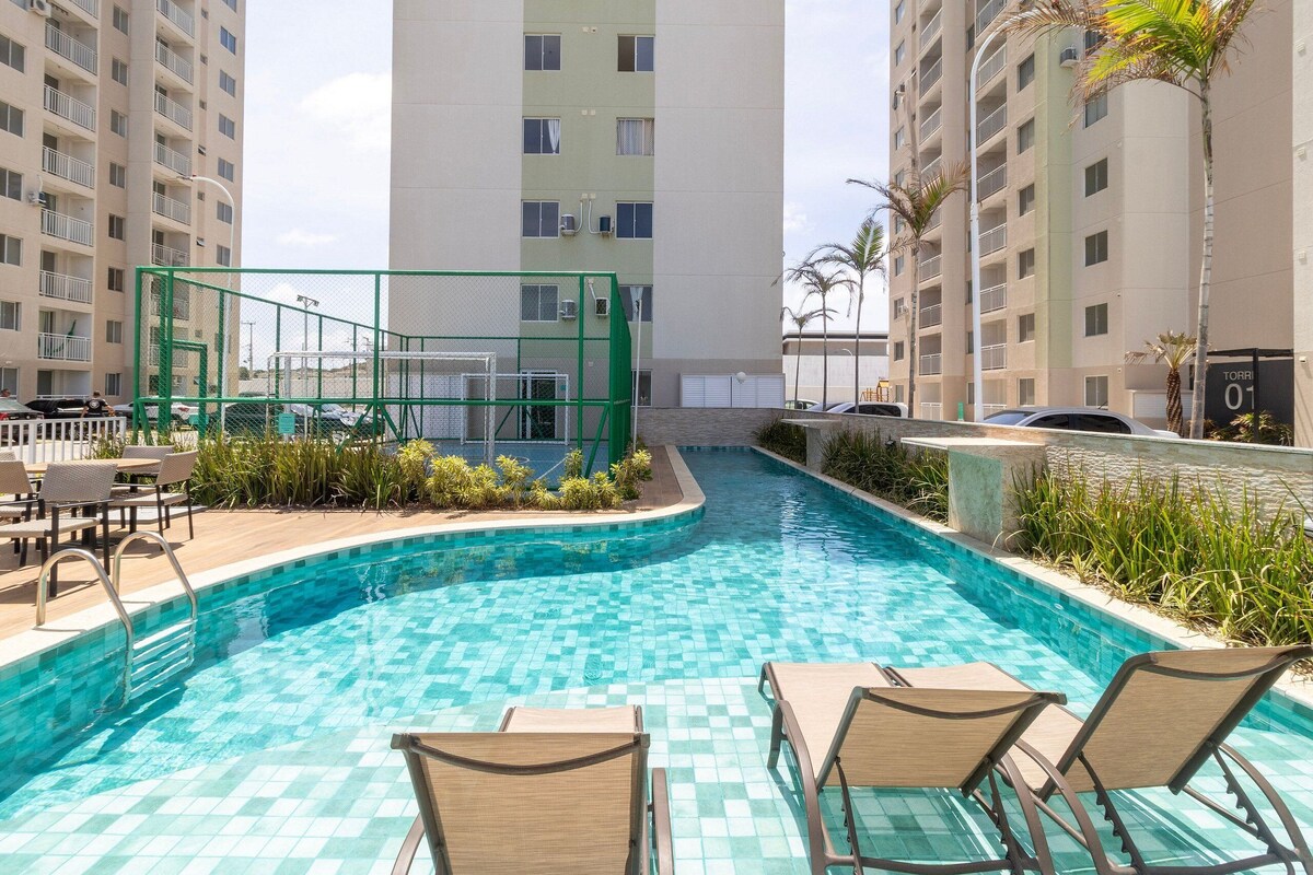 A swimming pool with checkered tiles, surrounded by lounge chairs and a small garden area.