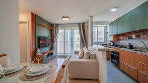 Una cucina moderna con zona pranzo, un divano e una TV che mostra 'NETFLIX'.