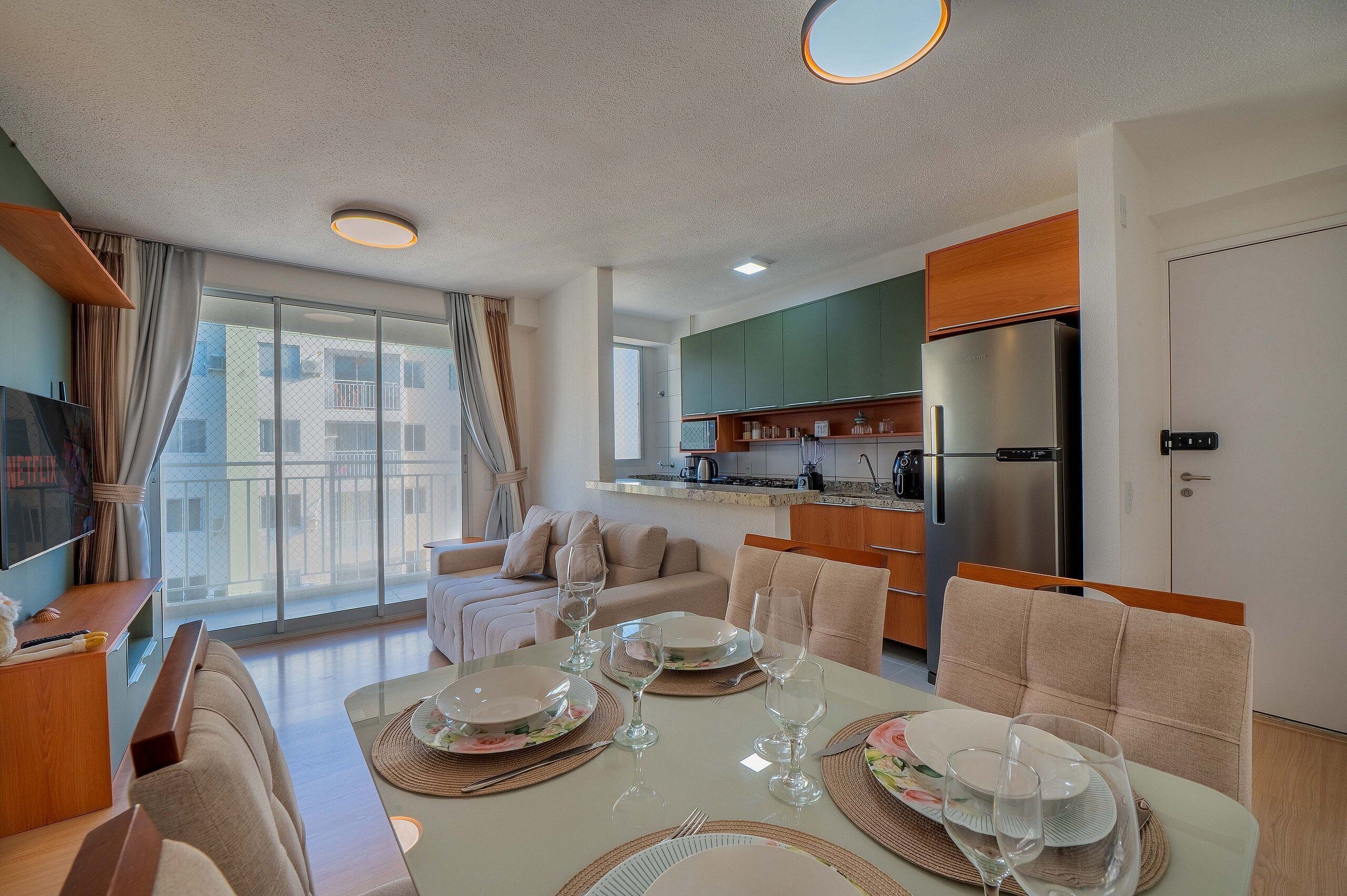 Una sala de estar moderna con comedor, ventanas amplias y una cocina al fondo.
