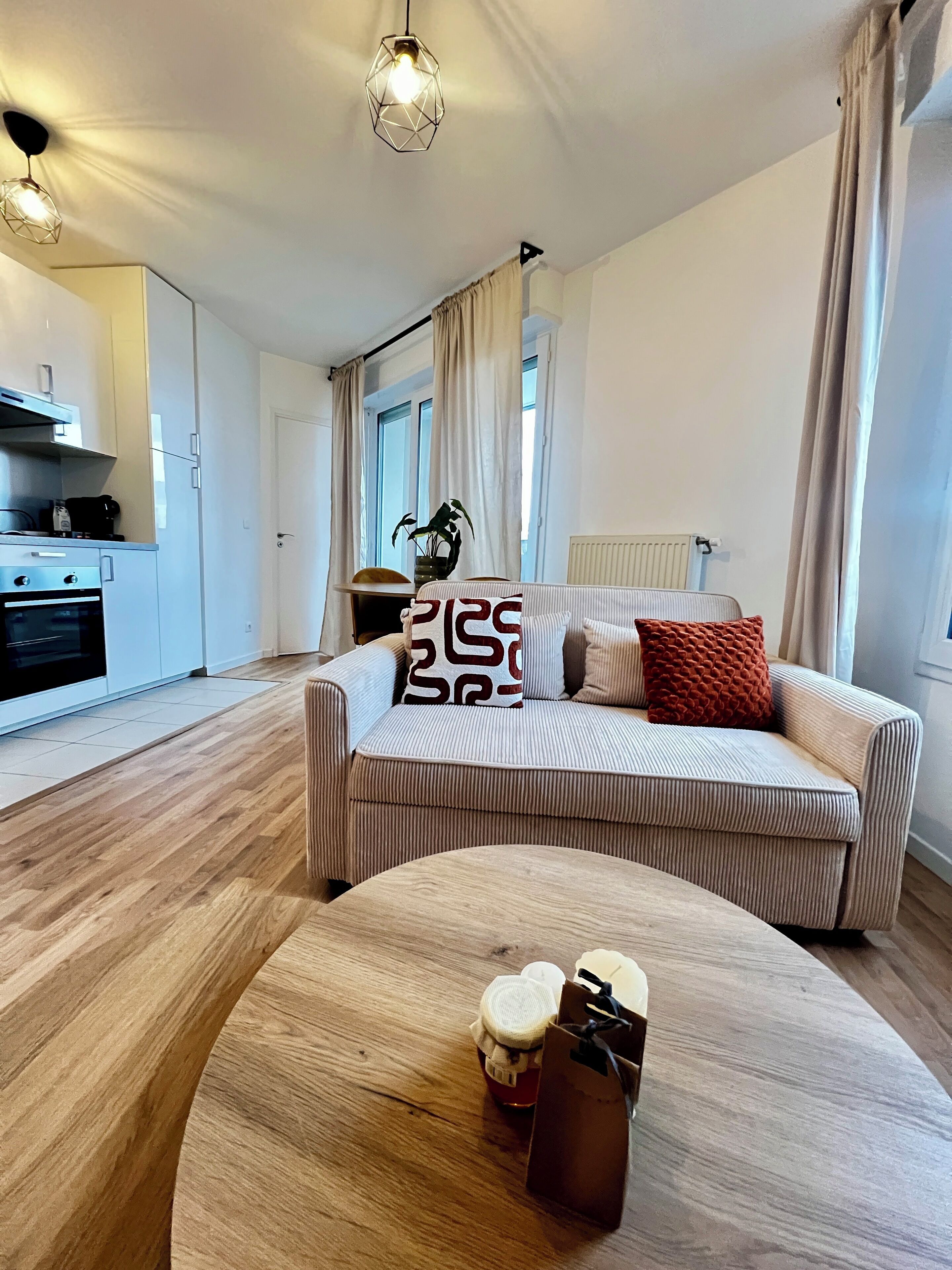 A modern living room with a sofa, a coffee table, and a kitchen in the background.