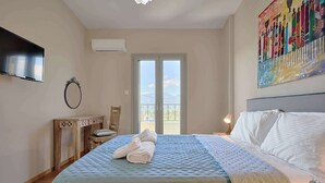 A bedroom with a bed, a TV, a painting, and a balcony. - Creta Leisure Escape, Private Pool & Garden Oasis (Pompia)