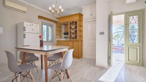 A kitchen with a dining table, chairs, and an air conditioning unit. - Creta Leisure Escape, Private Pool & Garden Oasis (Pompia)