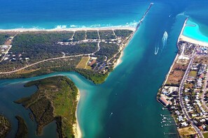 Vue aérienne d’une zone côtière comprenant un port de plaisance, des immeubles résidentiels et une zone forestière dense.